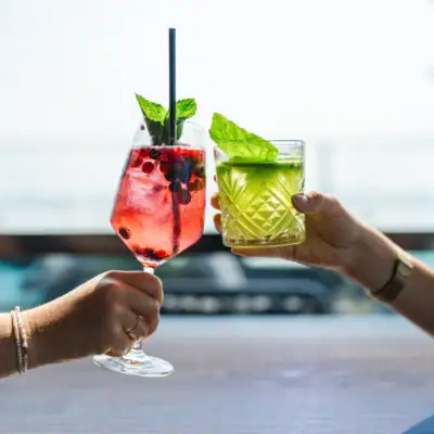 Two hands holding drinks with straws.