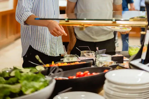 A man and a woman are standing at a buffet.