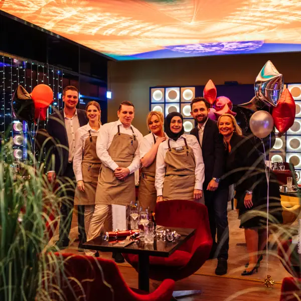 Various members of the aja Travemünde team are festively dressed and standing in the bar.