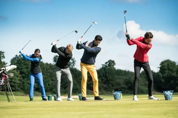A group of people play golf on a golf course.