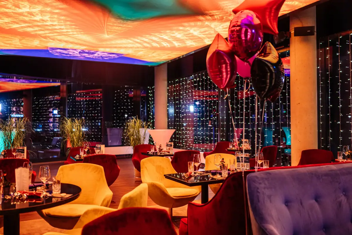 A room with tables, chairs and balloons.