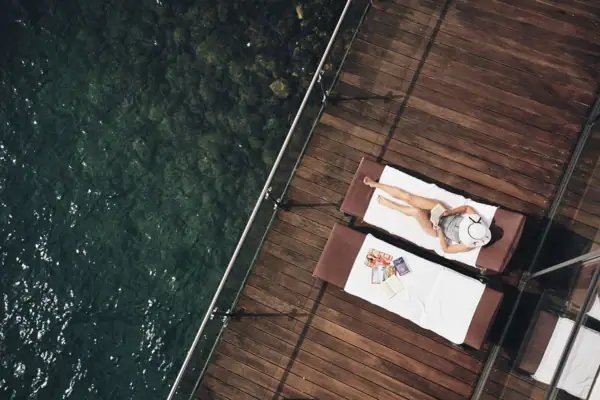 Liege am See Eine Frau liegt auf einem Liegestuhl neben Wasser.