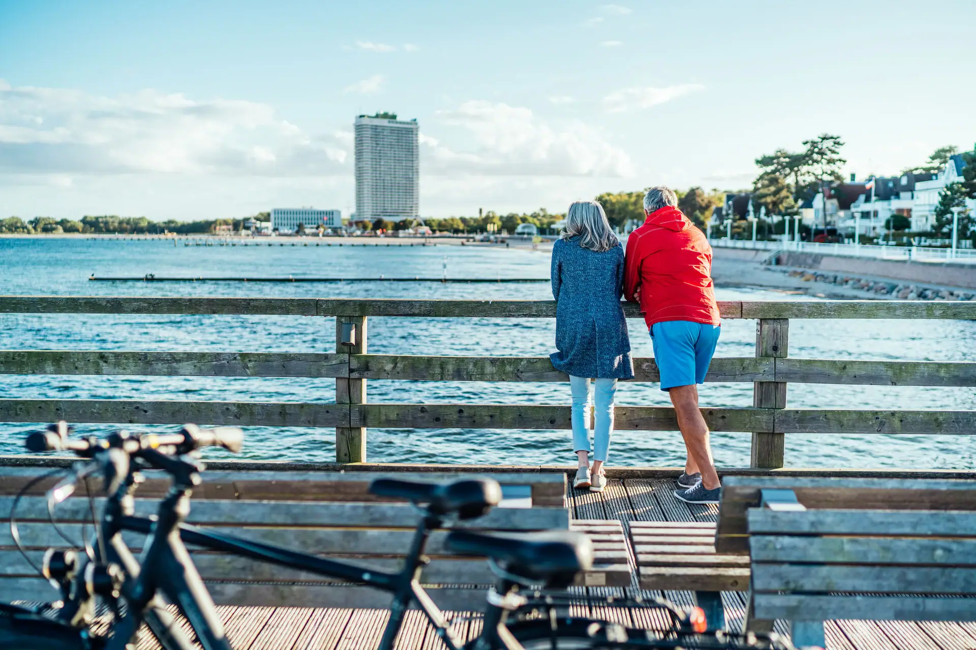 Couple by the sea A man and a woman stand on a wooden bridge and look out over the water.