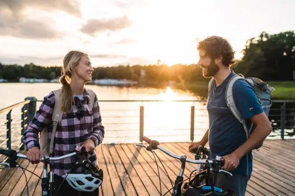 Bike tour A man and a woman are standing on a jetty in front of a lake with bicycles.