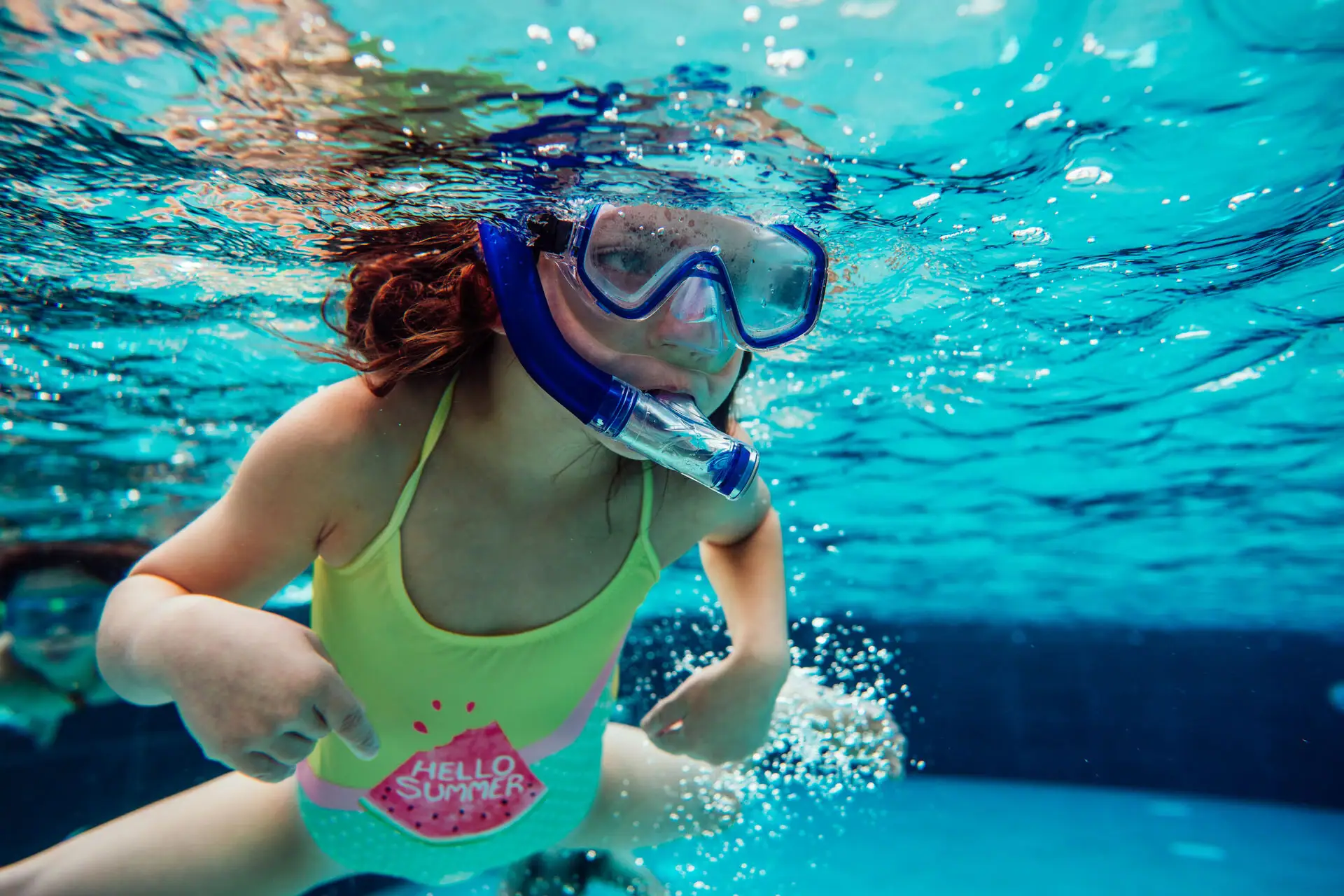 Girl dives A girl with diving goggles snorkelling underwater.