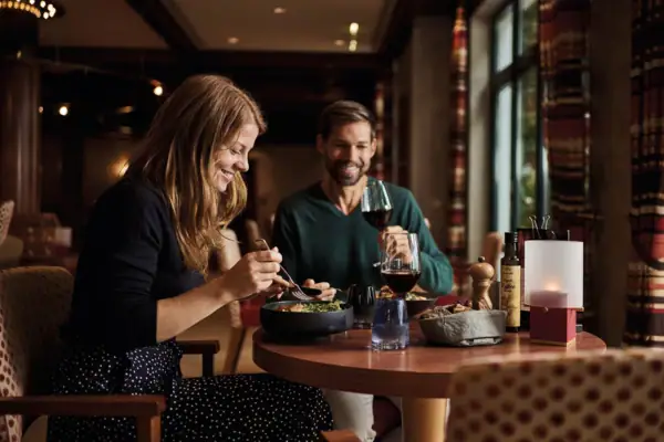 A man and a woman are eating at a table.