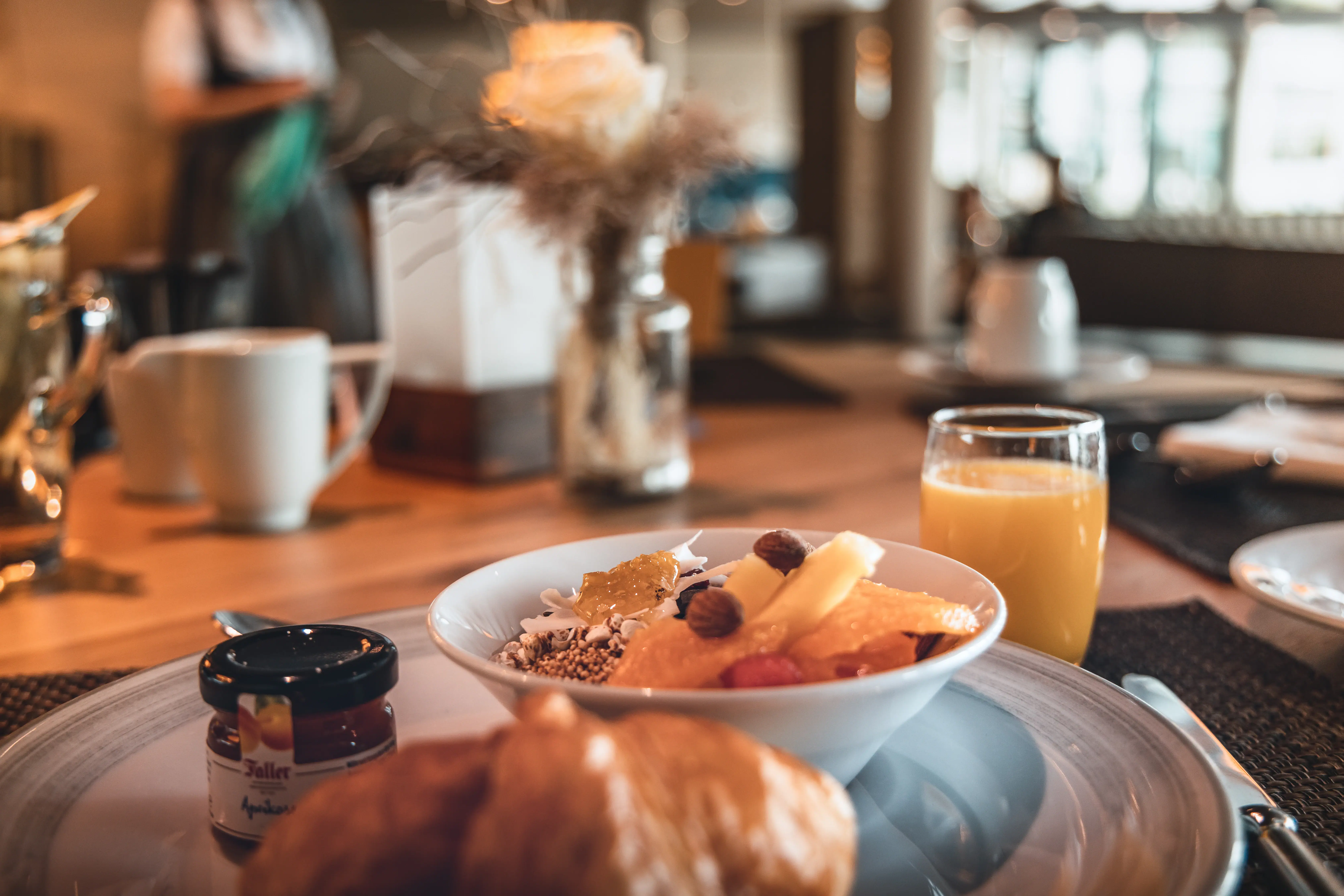 Bowl with fruit and croissant on a plate.