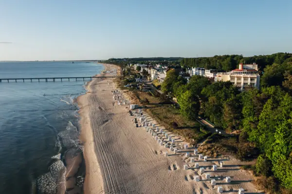 A beach with buildings and trees in the foreground.