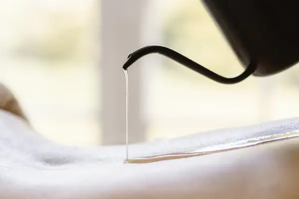 A person pours oil on the back of another person.