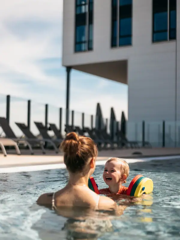 Woman and child in swimming pool with ball in the water.