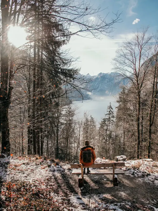 Winter in Ruhpolding A person is sitting on a bench overlooking a lake in a wintry landscape.