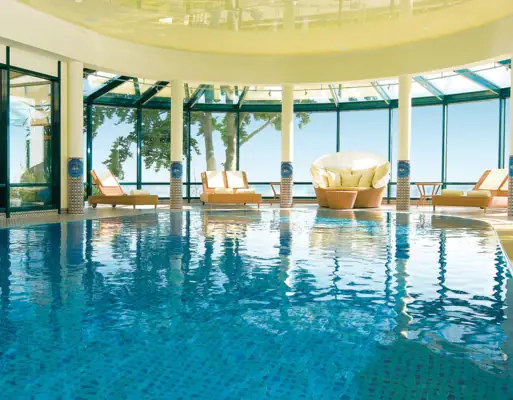 An indoor pool with chairs and a large ceiling.