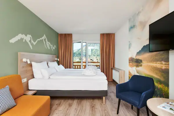 Room with bed and chair, equipped with pillows and bed linen.