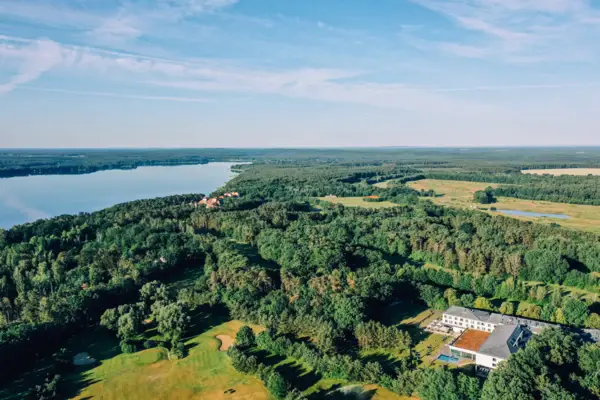 Aerial view of a large expanse of water with surrounding trees and a building.