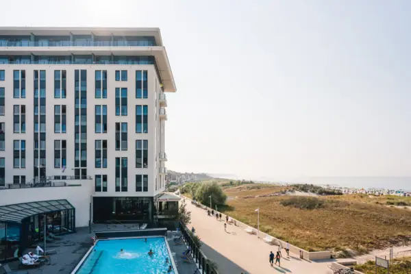 A building with a pool and people walking by.