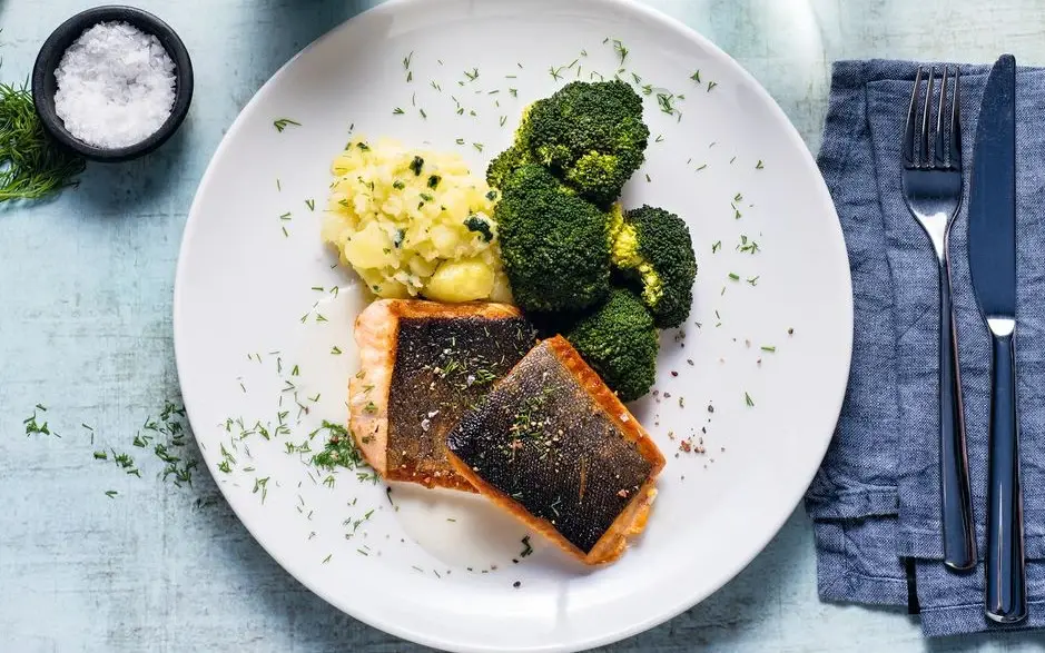 A dish of fish, broccoli and mashed potatoes is served on a plate. 