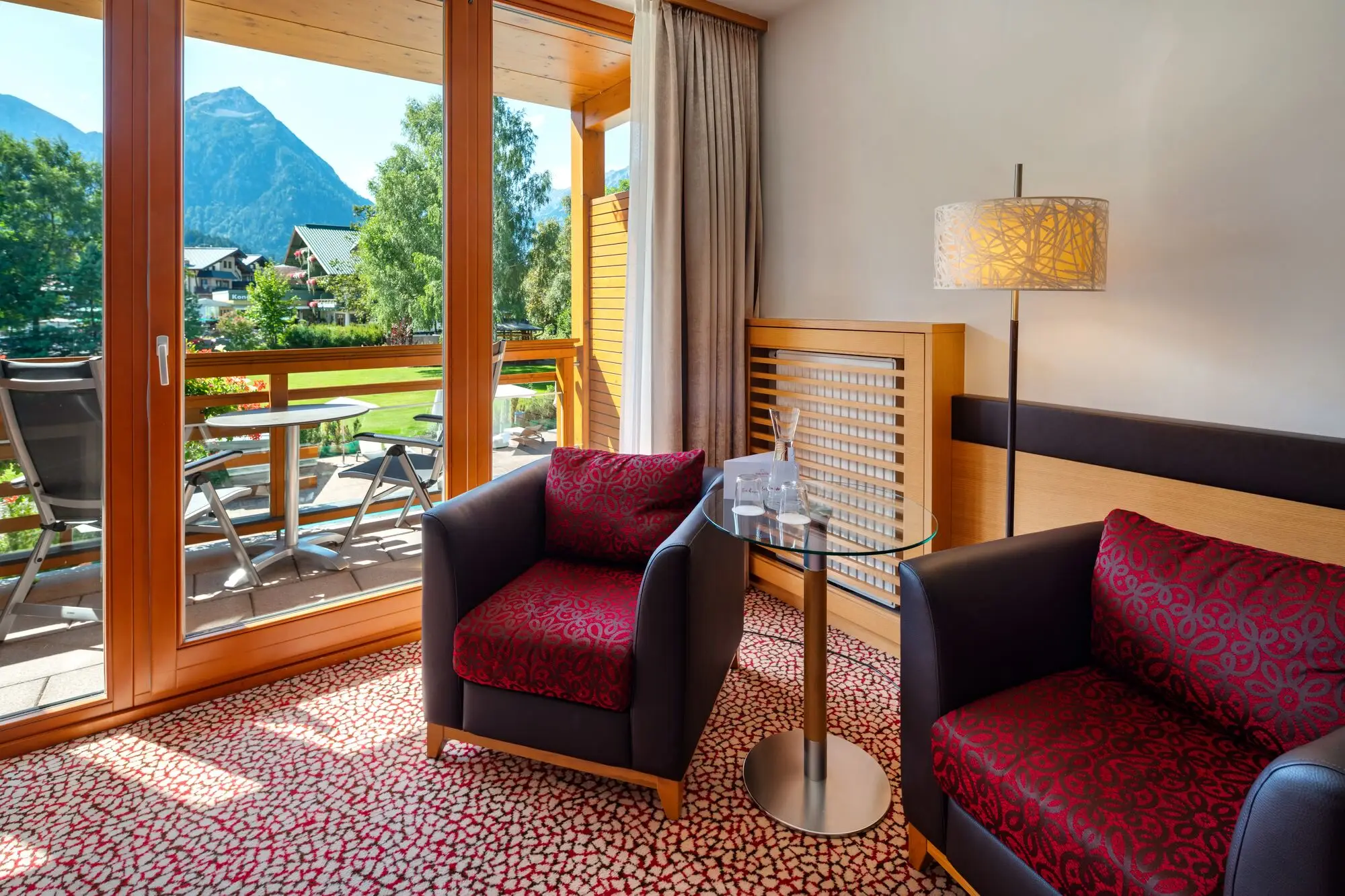 Interior with two armchairs and a table. In the background you can see a balcony with a view of the mountains.