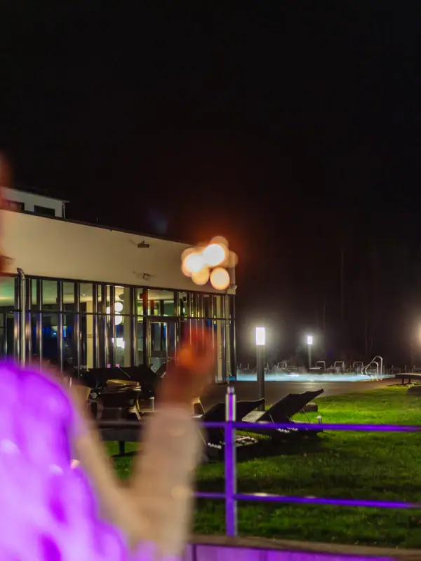 A person stands in front of the hotel holding sparklers in the night.