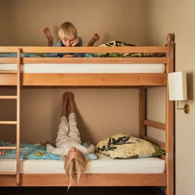 A boy lies on a bunk bed while a girl lies underneath.