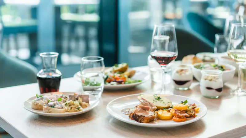A table with plates full of food and wine glasses.