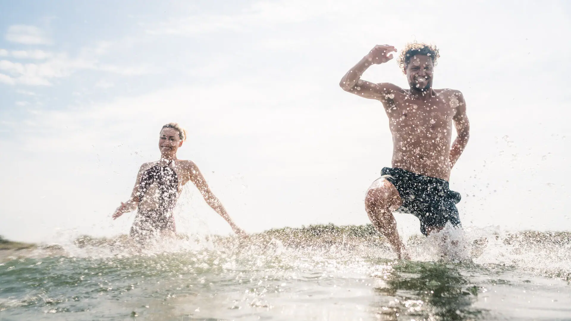 Two people are walking in the water.