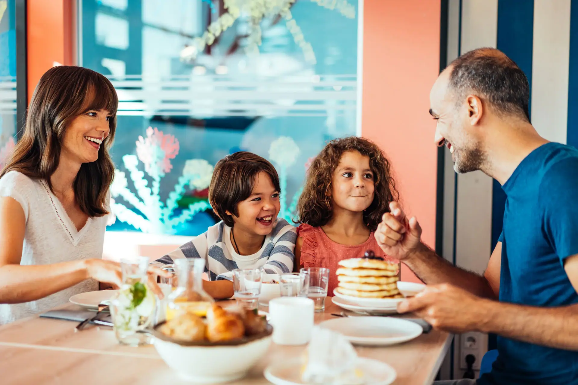 Family breakfast A group of people are sitting at a table with pancakes.