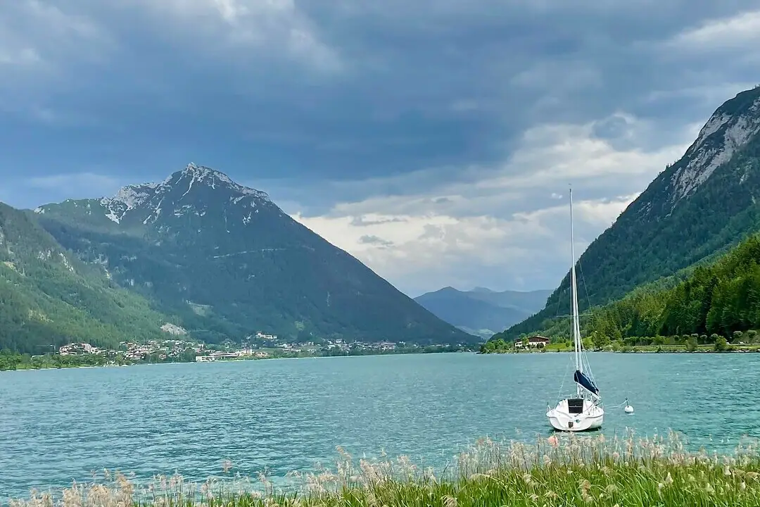 Boat Achensee A boat on a lake under a cloudy sky.