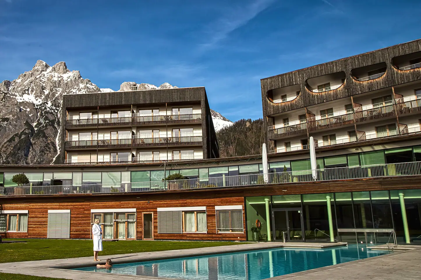 Person standing in front of an outdoor swimming pool.