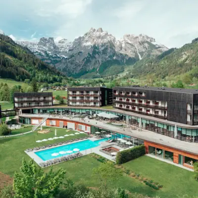A hotel with a swimming pool and mountains in the background
