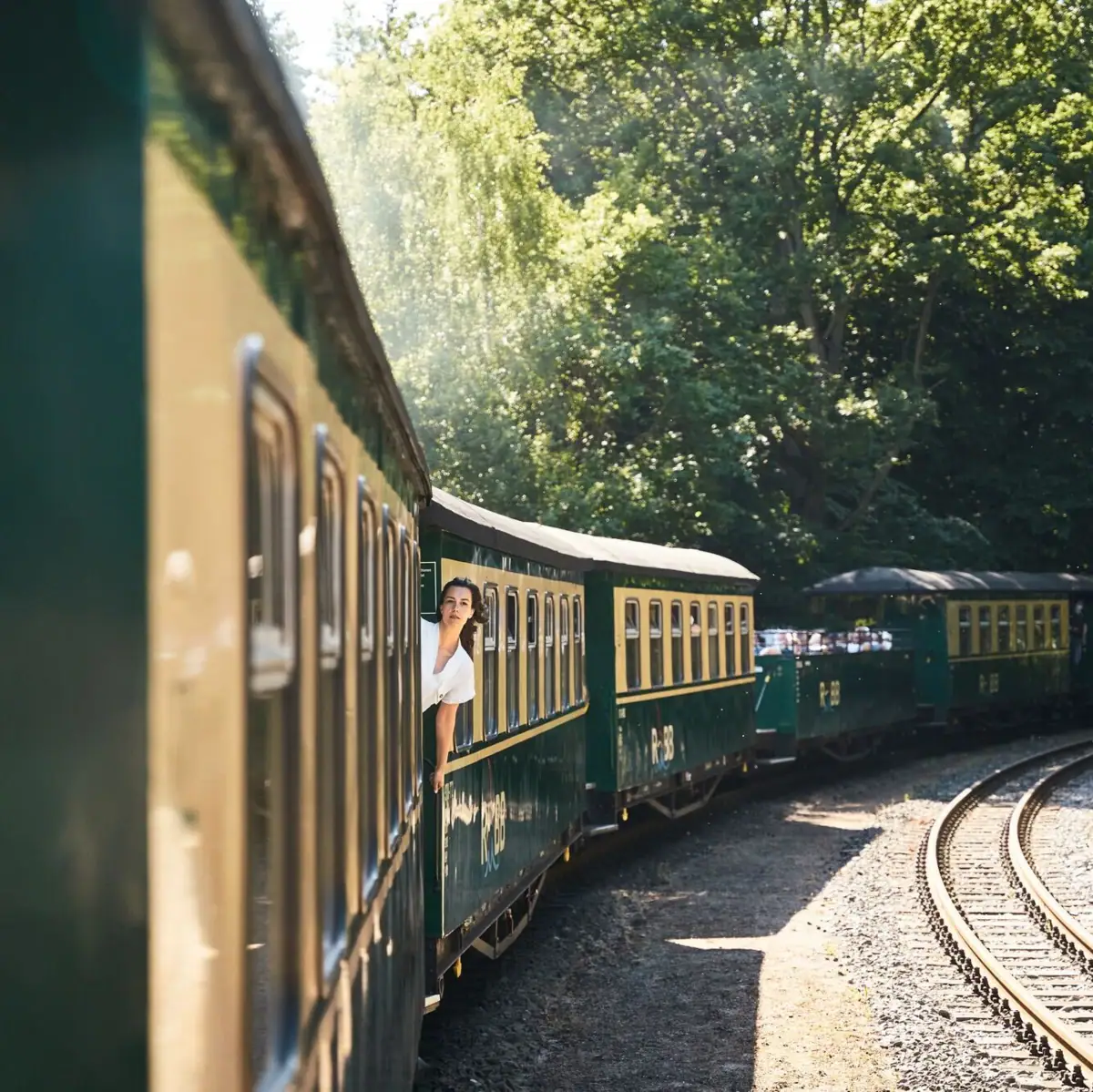 A woman leans out of a train window.