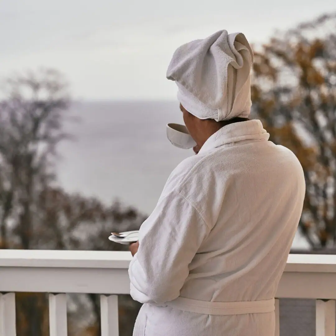Woman in bathrobe A person in a white bathrobe with a towel on their head and a cup of tea.