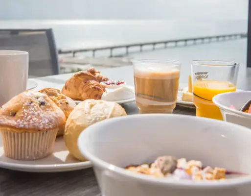 A table with pastries, crockery and drinks.