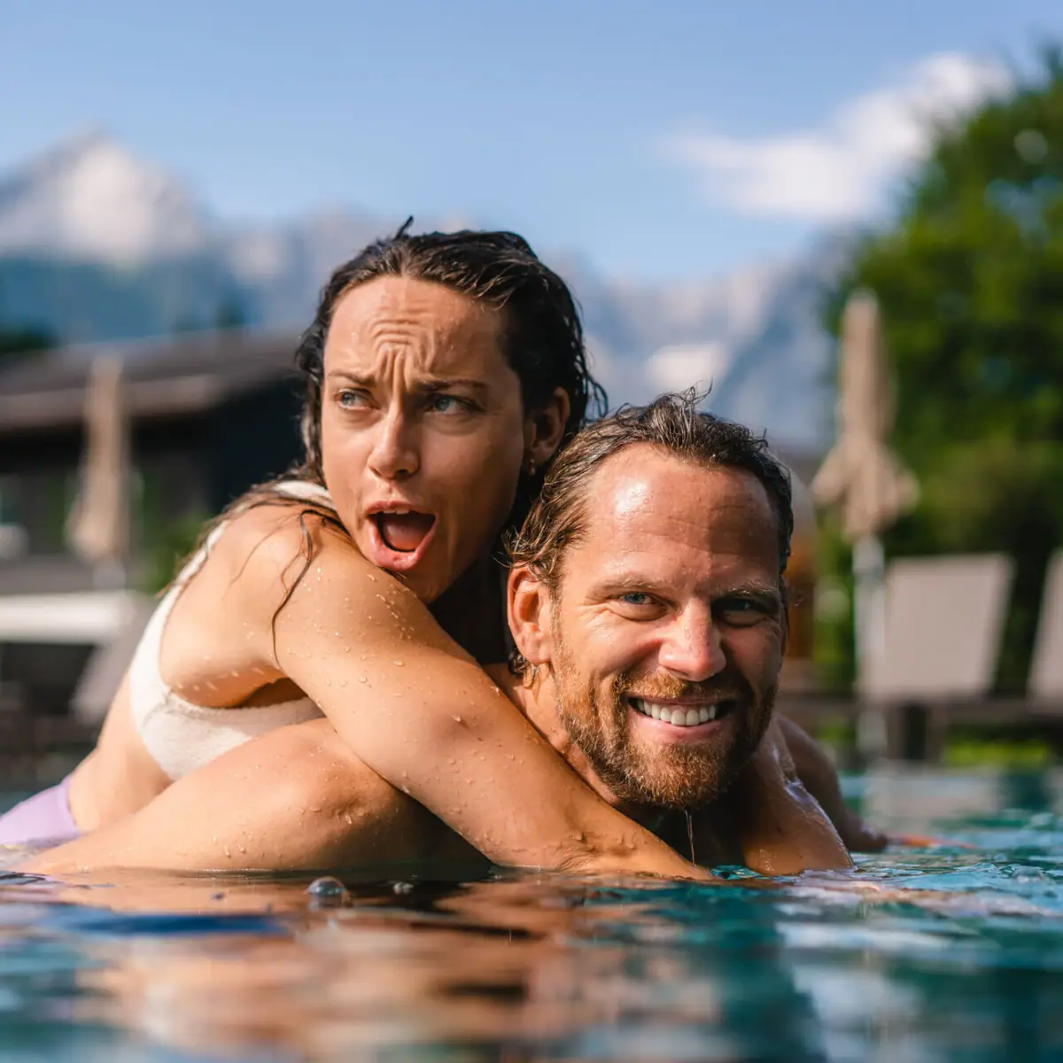 A man and a woman in a swimming pool, both smiling.