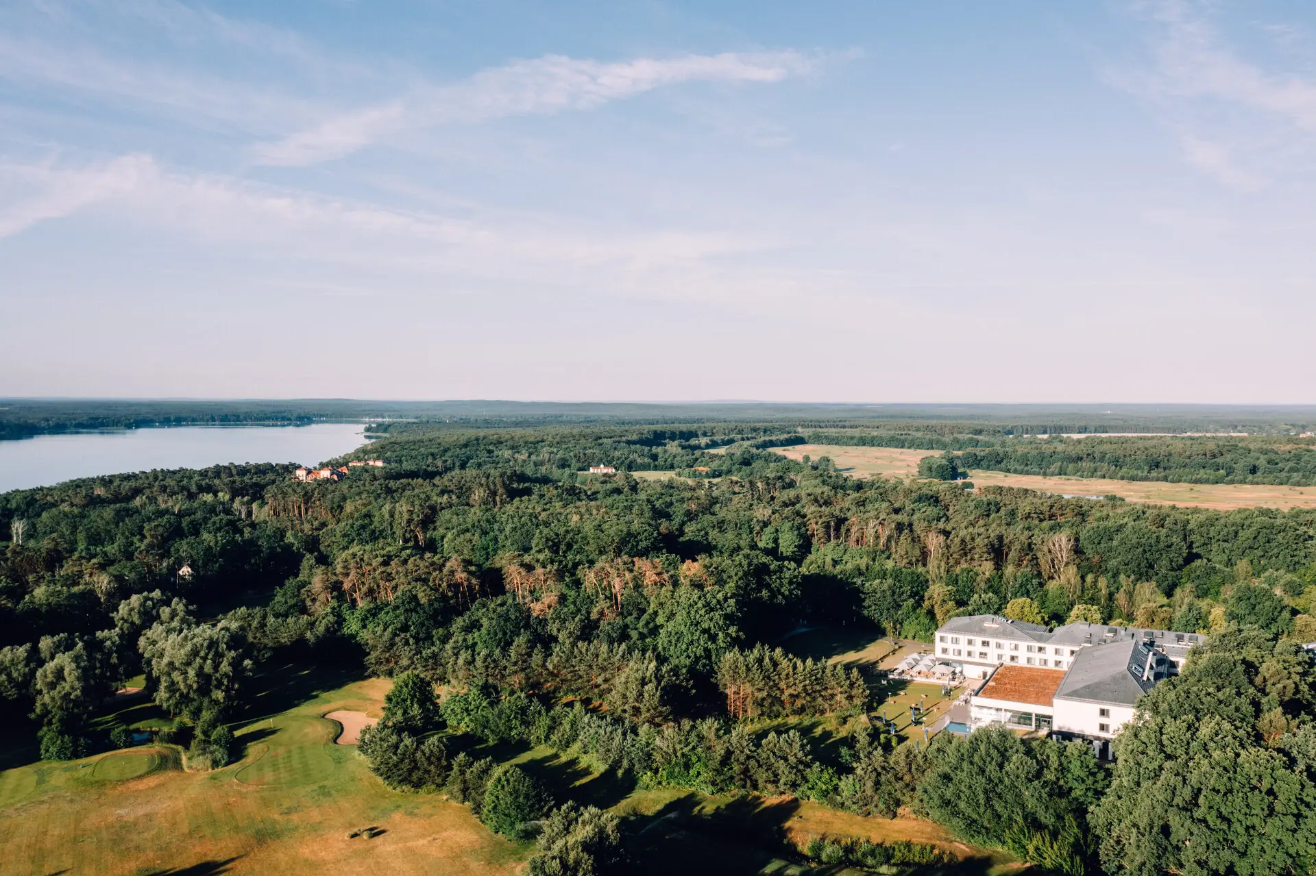 Building surrounded by trees with a lake in the background