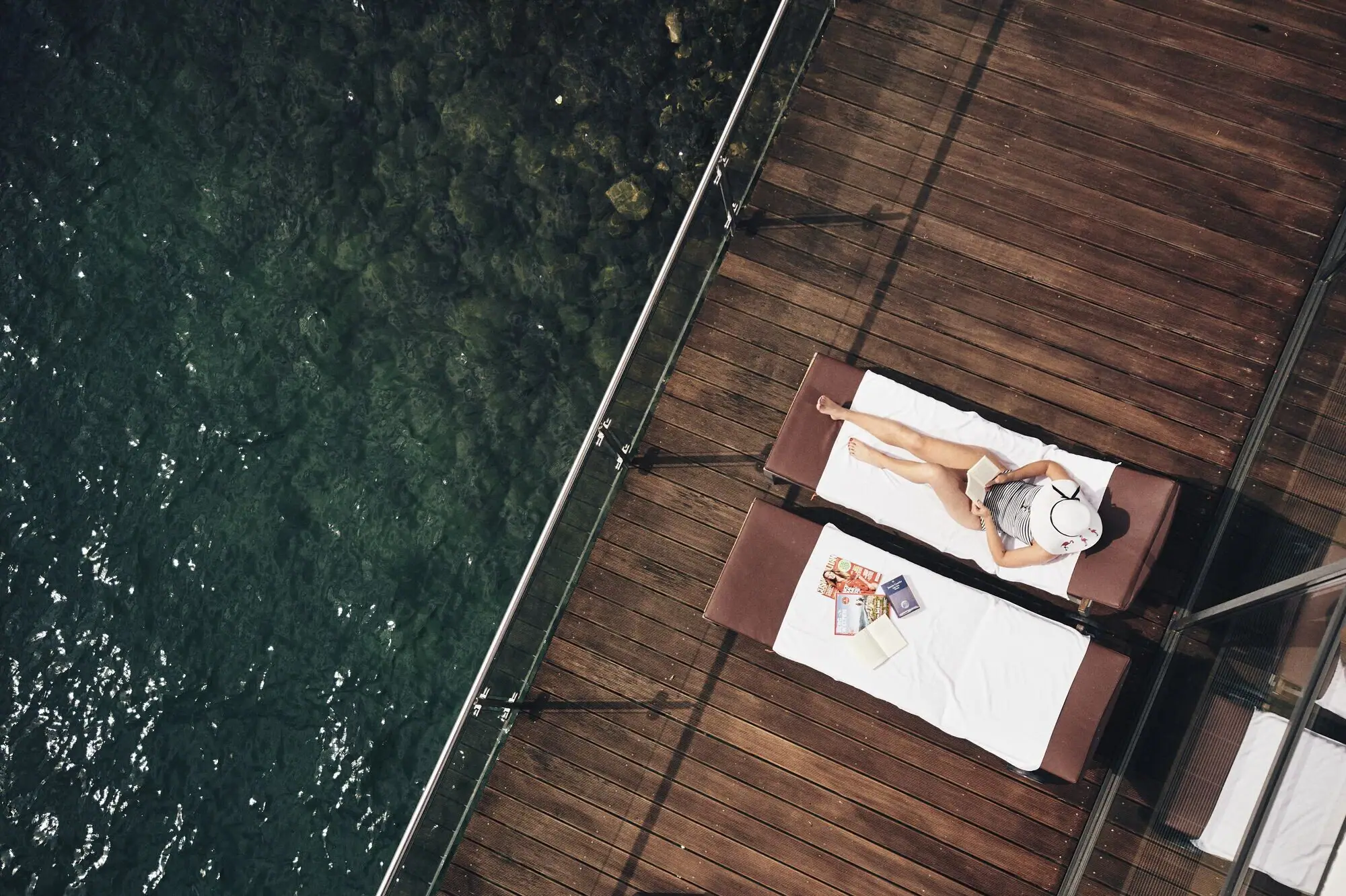 Lounger by the lake A woman lies on a deckchair next to water.