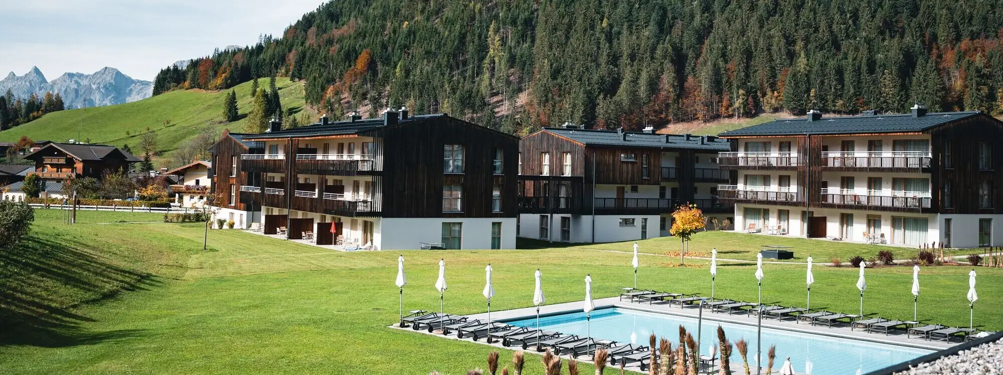 aja vacation apartments Werfenweng A building with a lawn and mountain backdrop.
