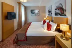 Rooms at Achensee A bed with pillows and a television in a hotel room on Lake Achensee.