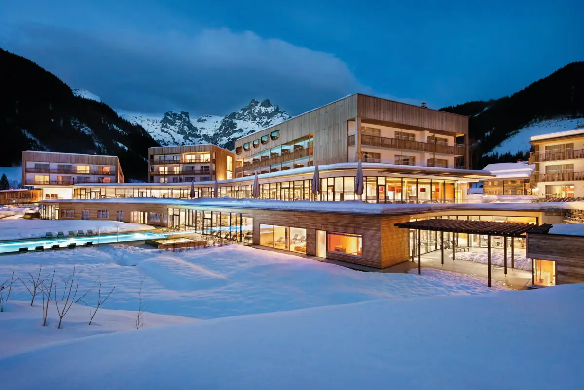 An illuminated hotel building on snow-covered ground.