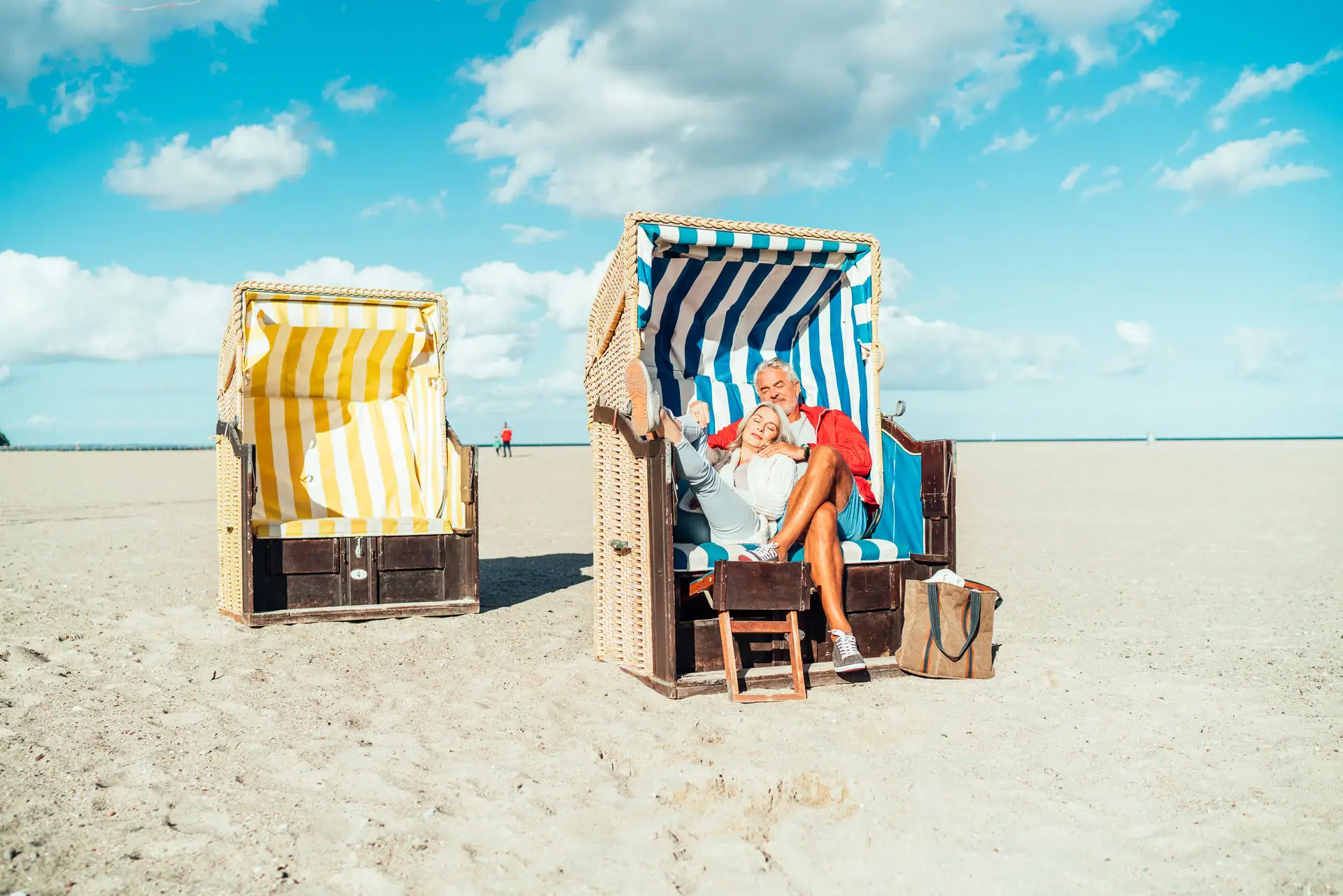 Ein Mann und eine Frau sitzen auf Stühlen am Strand.