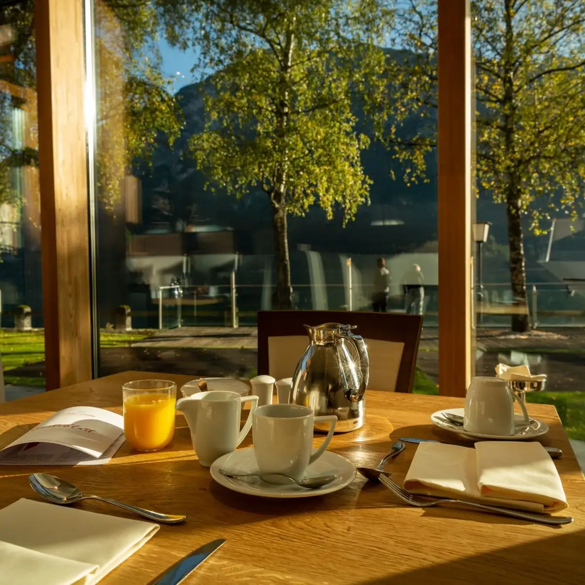 Breakfast A table with a tea service in front of a glass wall.