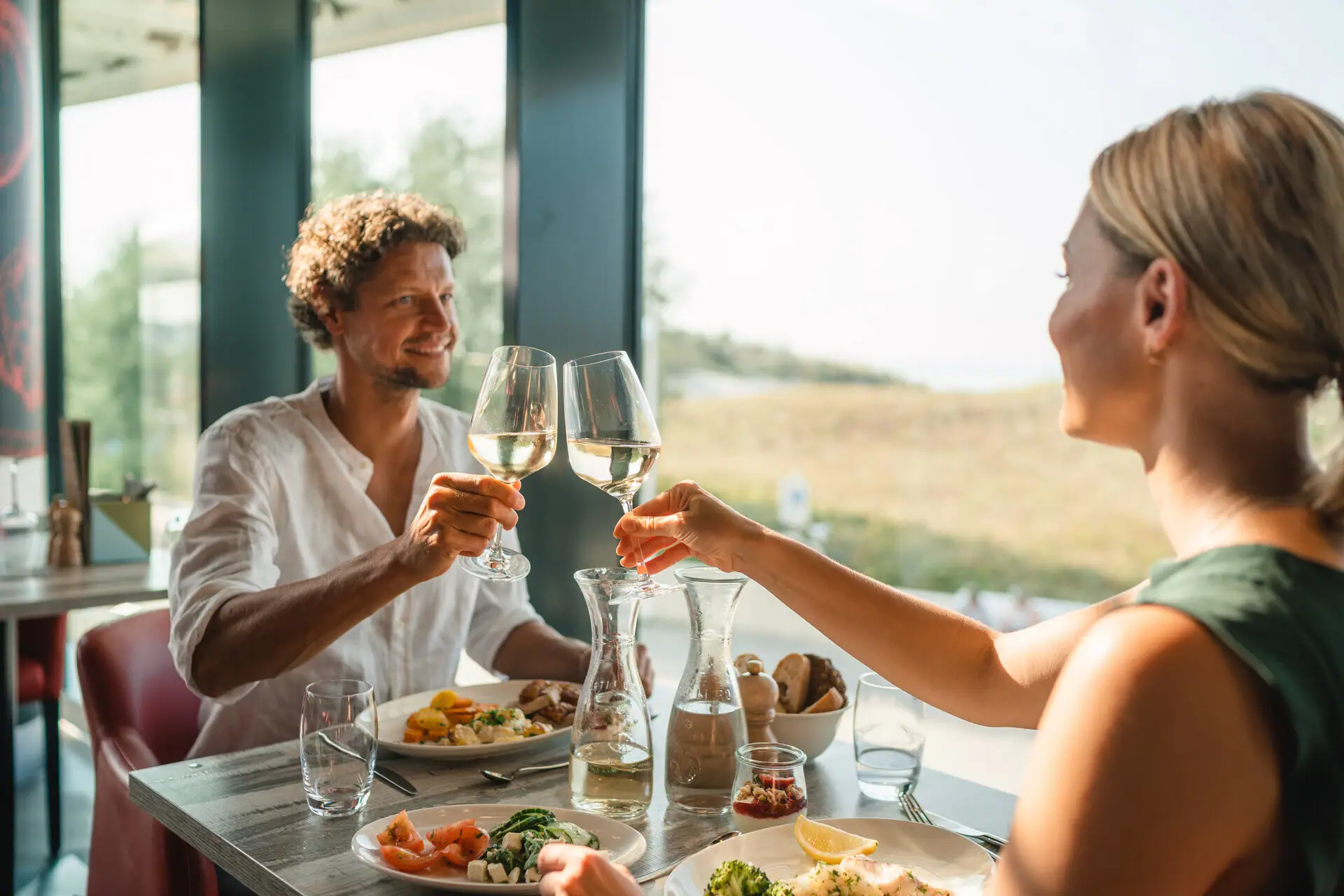 Dinner A man and a woman clink glasses of wine at a table.