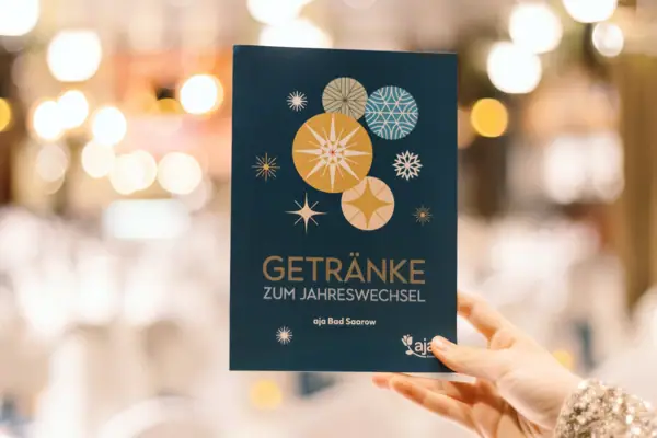 New Year's Eve offer at the aja Bad Saarow Hand holds a blue card with drinks written on it