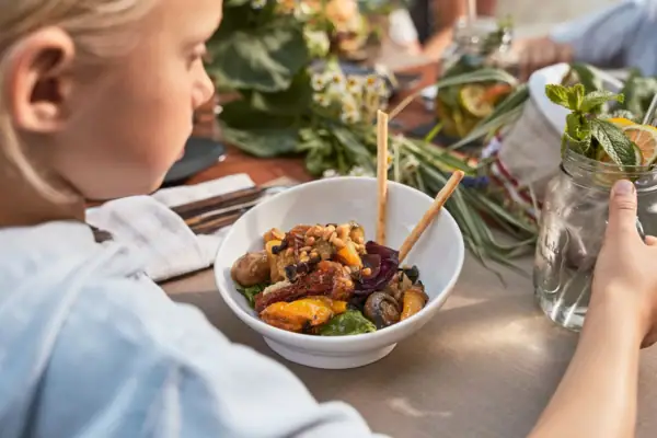 Person sits at a table with a bowl of food.