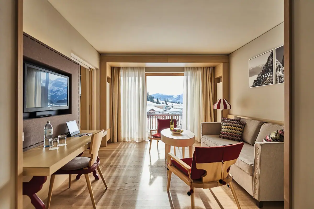 Suite living room A room with a table, chairs and a television.