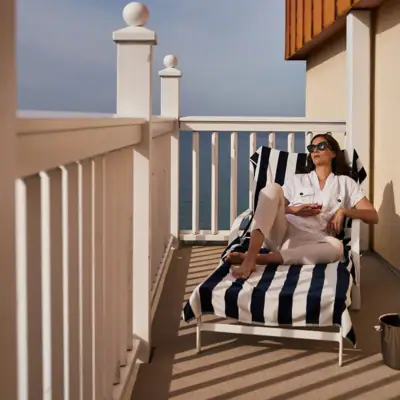 Balcony North Perd & Villas A woman sits on a chair on a deck.