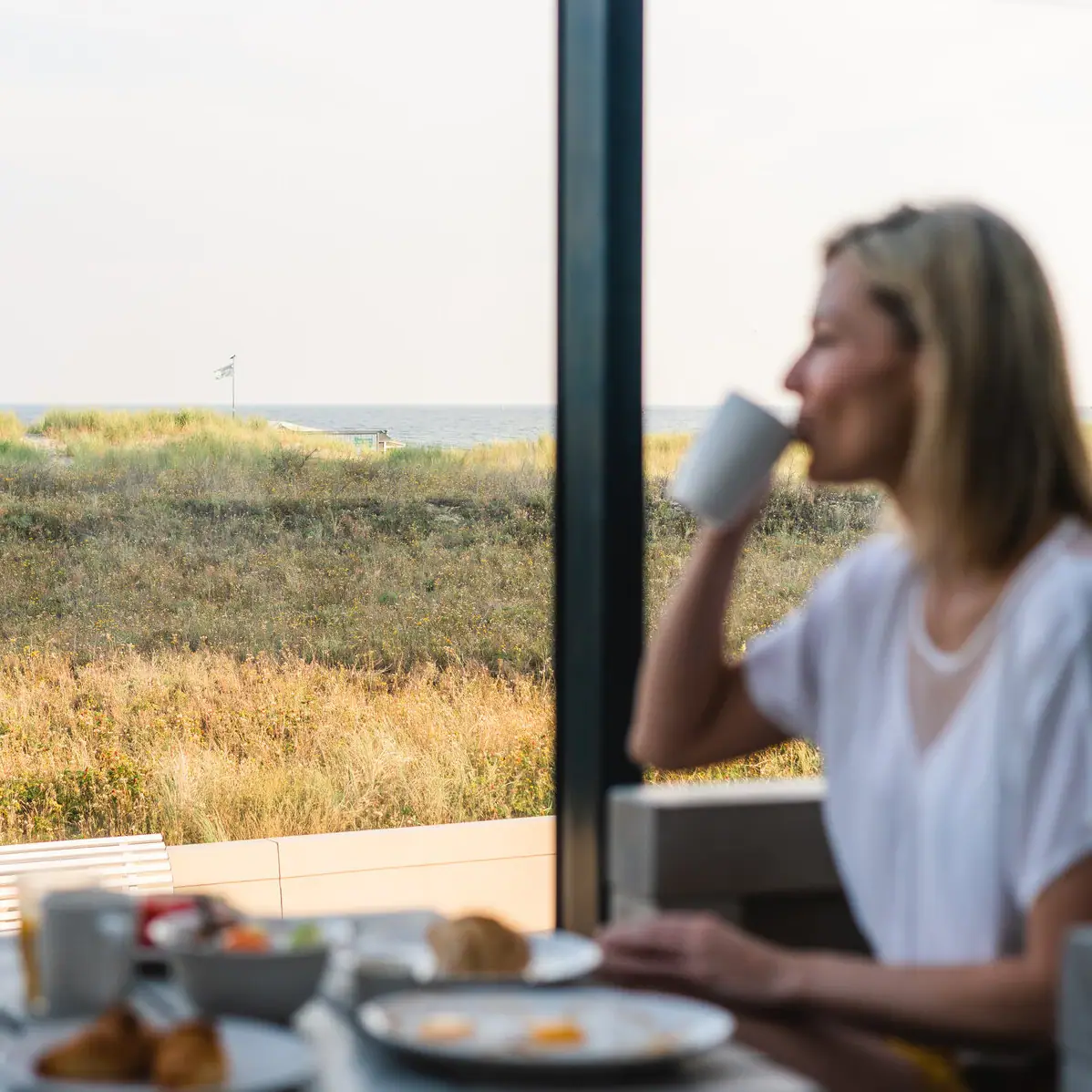 A woman is sitting at a table with a cup of coffee.