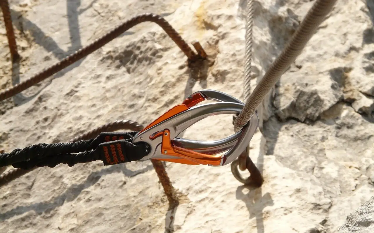 Close-up of a carabiner attached to a wire rope in a rock.