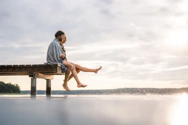A man and a woman are sitting on a footbridge.