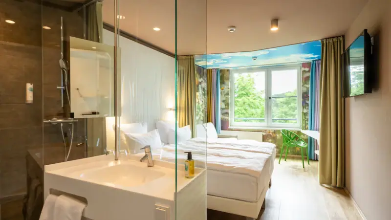 Rooms at the aja Bad Saarow A room with a glass shower and two beds.