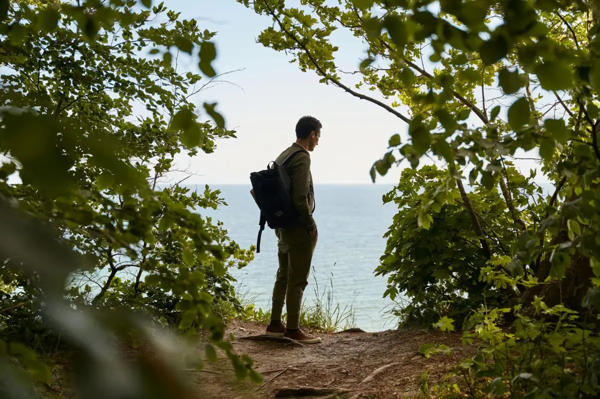 Rügen excursion A man with a rucksack stands on a hill while hiking.